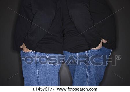 Stock Photo - Bodies of mid adult identical twin men standing back to back.. Fotosearch