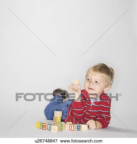 Boy lying on stomach propped up on elbows playing with toy blocks View Large Photo Image Stock Photo - Boy lying on stomach propped up on elbows playing with toy blocks. Fotosearch