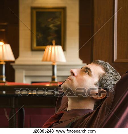 Businessman reclining with arms behind head looking up View Large Photo Image Stock Photo - Businessman reclining with arms behind head looking up. Fotosearch