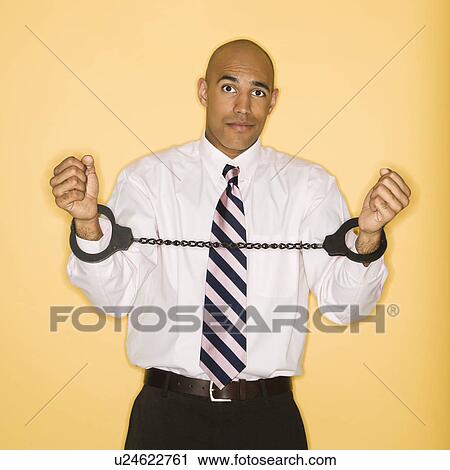 Stock Image - Businessman wearing handcuffs. Fotosearch