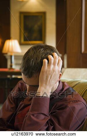Stock Image - Businessman with hand to head and eyes closed looking depressed.. Fotosearch