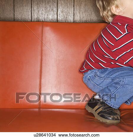 Caucasian boy kneeling on vinyl sofa. View Large Photo Image Picture - Caucasian boy kneeling on vinyl sofa.. Fotosearch