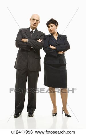 Caucasian middle-aged businessman and Filipino businesswoman standing with arms crossed against white background. View Large Photo Image Stock Image - Caucasian middle-aged businessman and Filipino businesswoman standing with arms crossed against white background.. Fotosearch