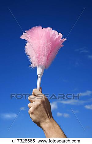 Stock Photography - Close up of young female adult hand holding feather duster against sky. Fotosearch