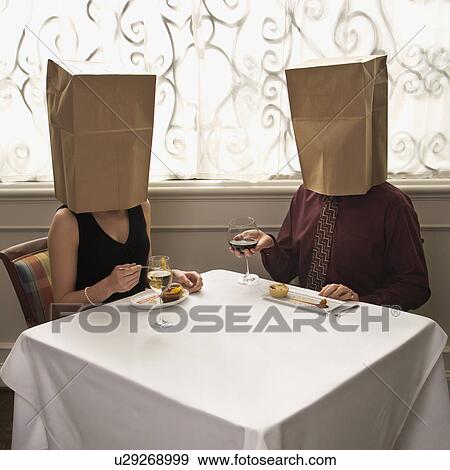 Stock Photo - Couple dining in a restaurant with paper bags over heads. Fotosearch