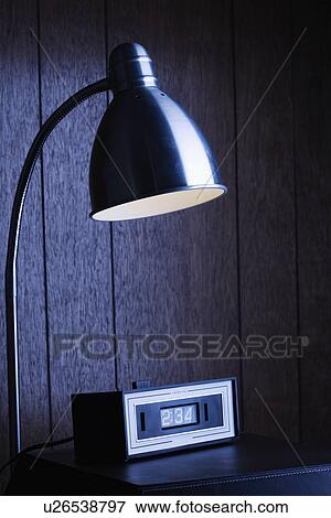 Dim desk lamp and retro clock against wood paneling at night View Large Photo Image Stock Photo - Dim desk lamp and retro clock against wood paneling at night. Fotosearch