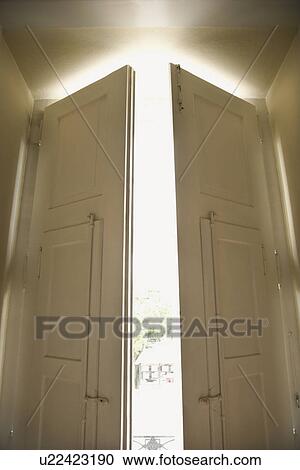 Stock Image - Doors opening with sunlight streaming in. Fotosearch