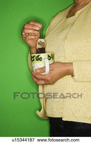 Stock Photo - Female dipping tea bag in mug. Fotosearch