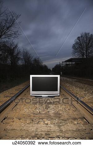 Stock Image - Flat panel television set on railroad tracks at night. Fotosearch