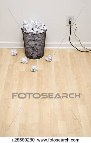 Stock Image - Full wire mesh trash can with crumpled paper next to electrical outlet and plugs. Fotosearch