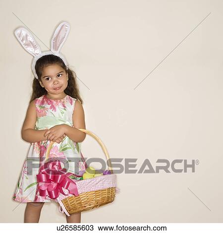 Girl wearing bunny ears holding Easter basket View Large Photo Image Stock Image - Girl wearing bunny ears holding Easter basket. Fotosearch