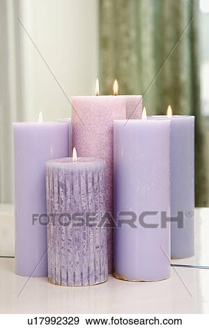 Stock Photo - Group of purple candles burning in front of mirror. Fotosearch