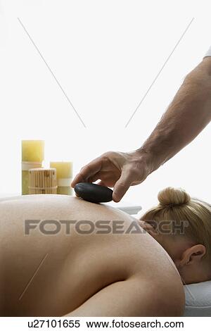 Male massage therapist placing hot stone on back of woman laying on massage table View Large Photo Image Stock Photography - Male massage therapist placing hot stone on back of woman laying on massage table. Fotosearch