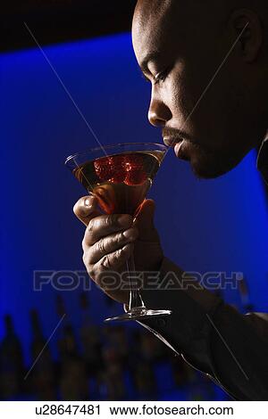Man drinking martini in bar against glowing View Large Photo Image Stock Image - Man drinking martini in bar against glowing. Fotosearch