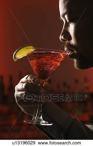 Man drinking martini in bar against glowing red background. View Large Photo Image Stock Photo - Man drinking martini in bar against glowing red background.. Fotosearch