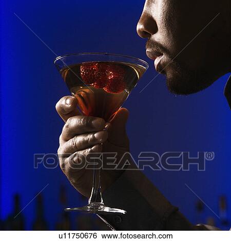 man drinking martini in bar against glowing blue background View Large Photo Image Stock Photograph - man drinking martini in bar against glowing blue background. Fotosearch