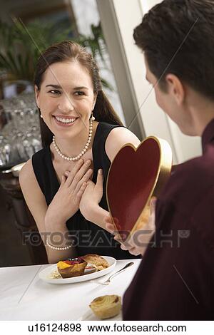 Stock Photo - Man giving a heart shaped box of chocolates to woman . Fotosearch