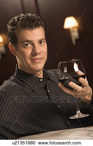 Stock Image - Man holding glass of red wine. Fotosearch