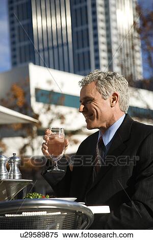 Man in suit sitting outside drinking water View Large Photo Image Stock Photography - Man in suit sitting outside drinking water. Fotosearch