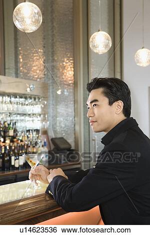 Stock Photograph - Man sitting at bar with drink. Fotosearch