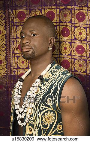 Stock Photo - Man wearing embroidered African vest and beads. Fotosearch