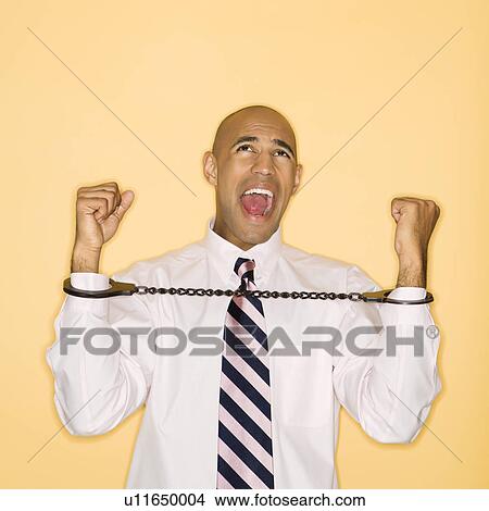 Picture - Man wearing handcuffs and screaming. Fotosearch