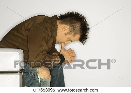 Stock Photography - man with mohawk sitting with hands to face . Fotosearch
