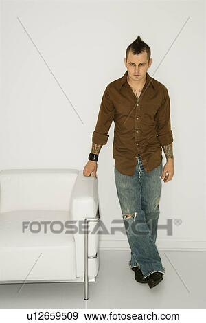 Man with mohawk standing beside white chair View Large Photo Image Stock Photo - Man with mohawk standing beside white chair . Fotosearch