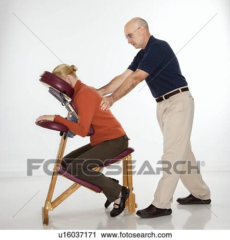 Massage therapist massaging back of woman sitting in massage chair View Large Photo Image Stock Image - Massage therapist massaging back of woman sitting in massage chair. Fotosearch