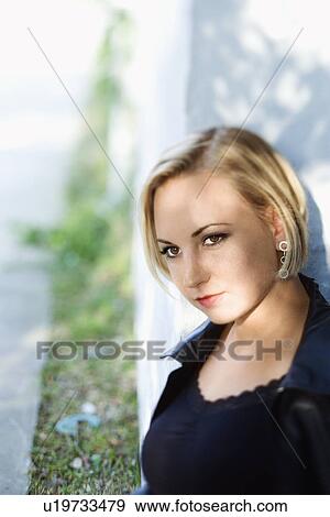 Mid-adult blonde woman standing against sun dappled building View Large Photo Image Stock Photo - Mid-adult blonde woman standing against sun dappled building. Fotosearch
