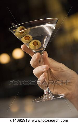 Mid adult female hand holding a martini with three olives View Large Photo Image Stock Image - Mid adult female hand holding a martini with three olives. Fotosearch