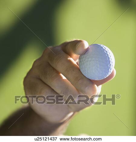 Stock Photo - Mid adult male hand holding golf ball. Fotosearch