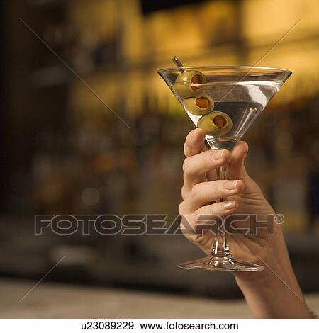 Mid adult woman's hand holding a martini with three olives View Large Photo Image Stock Photo - Mid adult woman's hand holding a martini with three olives. Fotosearch