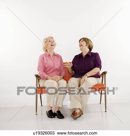 Middle aged woman and senior woman sitting and laughing View Large Photo Image Stock Image - Middle aged woman and senior woman sitting and laughing. Fotosearch
