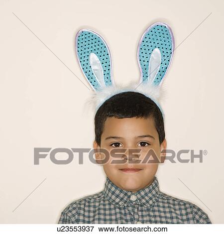 Stock Photo - Portrait of boy wearing bunny ears looking at viewer. Fotosearch