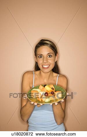 Portrait of young adult woman holding a plate of fruit View Large Photo Image Stock Image - Portrait of young adult woman holding a plate of fruit. Fotosearch