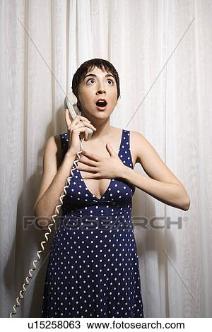Pretty Caucasian young woman holding telephone receiver to ear looking shocked. View Large Photo Image Stock Image - Pretty Caucasian young woman holding telephone receiver to ear looking shocked.. Fotosearch