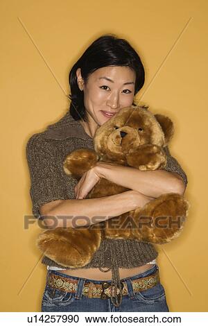 Stock Image - Pretty mid adult woman hugging brown teddy bear. Fotosearch
