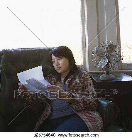 Pretty young Asian woman sitting in green chair reading letter. View Large Photo Image Stock Image - Pretty young Asian woman sitting in green chair reading letter.. Fotosearch
