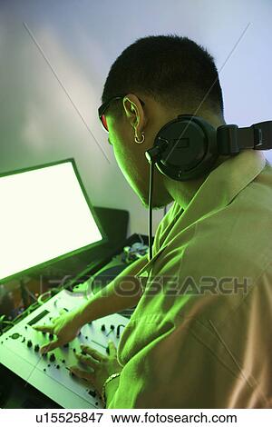 Rear view of Asian young adult male DJ mixing music on equipment. View Large Photo Image Stock Photo - Rear view of Asian young adult male DJ mixing music on equipment.. Fotosearch