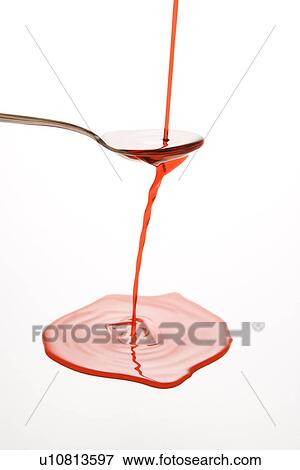Stock Photo - red cough syrup overflowing spoon . Fotosearch