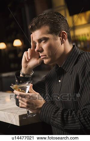 Side view of mid adult man holding martini with hand to head thinking View Large Photo Image Stock Image - Side view of mid adult man holding martini with hand to head thinking. Fotosearch