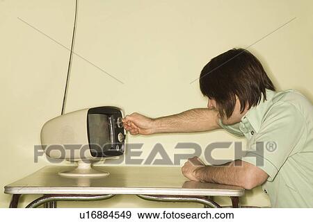 Side view of mid-adult man sitting at 50s retro dinette set turning old television knob. View Large Photo Image Stock Photo - Side view of mid-adult man sitting at 50s retro dinette set turning old television knob.. Fotosearch