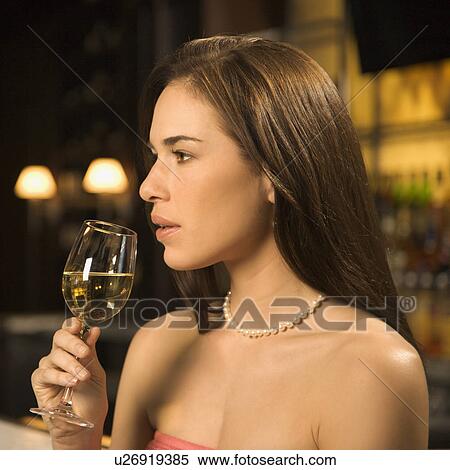 Side view of woman sitting at bar drinking glass of white wine View Large Photo Image Stock Photography - Side view of woman sitting at bar drinking glass of white wine. Fotosearch