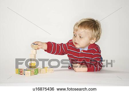 Stock Photograph - Studio portrait of young boy playing with toy blocks.. Fotosearch