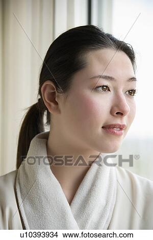 Taiwanese mid adult woman in bathrobe looking out window. View Large Photo Image Picture - Taiwanese mid adult woman in bathrobe looking out window.. Fotosearch