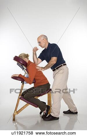 Stock Photo - therapist massaging a woman's back sitting in massage chair with his elbow. . Fotosearch