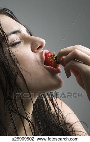 Stock Image - Woman biting a strawberry. Fotosearch
