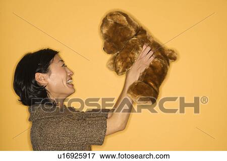 Stock Photo - Woman holding brown teddy bear and smiling. Fotosearch