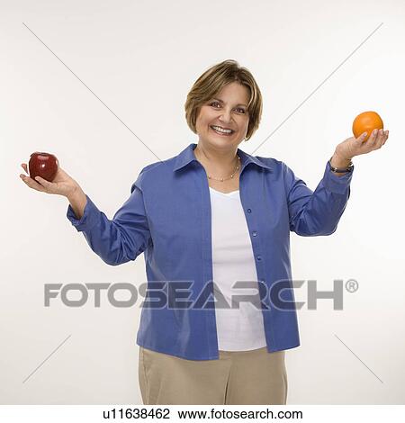 Stock Image - woman holding fruit in outstretched arms and smiling . Fotosearch